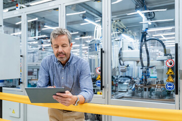 Engineer monitoring automation process with tablet in modern factory