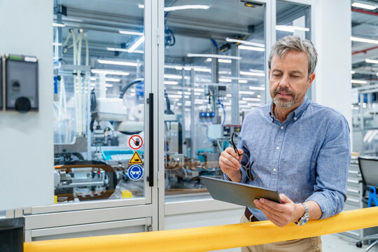 Engineer using tablet for quality control in automated factory indoors