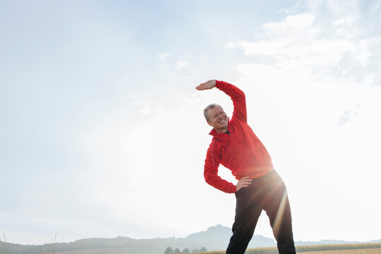Mid adult man exercising under sky on sunny day