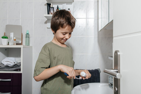 Child brushing teeth with toothbrush and toothpaste in bathroom