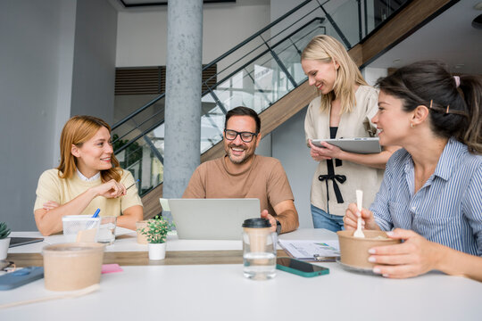 Cheerful team working together with healthy food in modern office