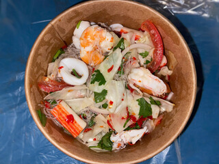 Thai seafood glass noodle salad in a bowl, featuring prawns, squid, vegetables, and spicy tangy dressing.