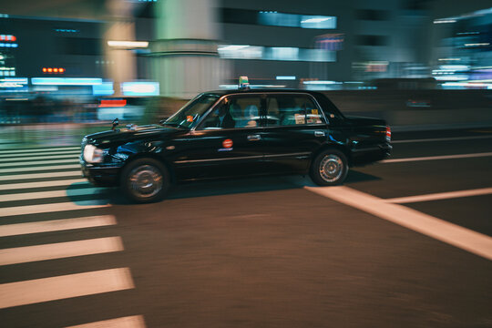Taxi in motion on illuminated city street at night Osaka Japan