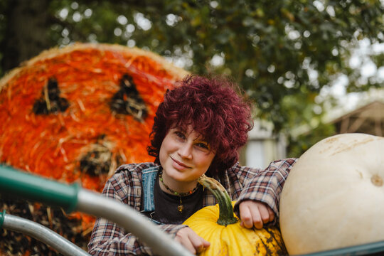 Smiling curly haired teen at pumpkin patch during autumn harvest