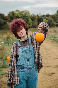 Teenager holding pumpkin in plaid shirt at outdoor autumn pumpkin patch