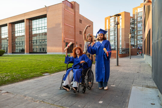 Graduates celebrating with a mother on a university campus outdoors