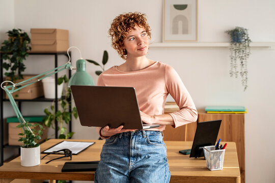Focused woman with laptop in organized plant-filled home office