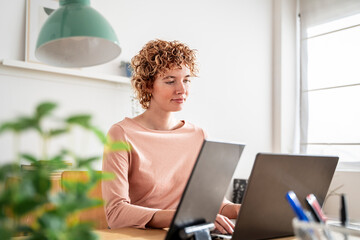 Businesswoman using multiple laptops working efficiently at a home office
