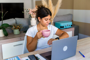Woman multitasking in home office with coffee and checking time