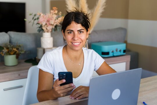 Smiling woman at home office using smartphone for online communication