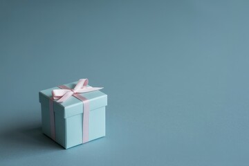 Obraz premium Gift box with pink ribbon on blue backdrop in studio shot for presents