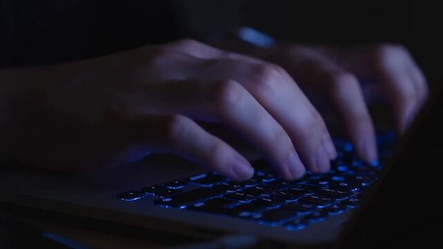 Typing fast on a laptop in the dark, coding or working late, a digital lifestyle concept