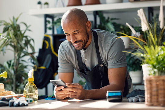 Entrepreneur in plant store using smartphone at indoor counter