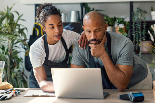 Entrepreneurs in plant store planning business strategy on laptop