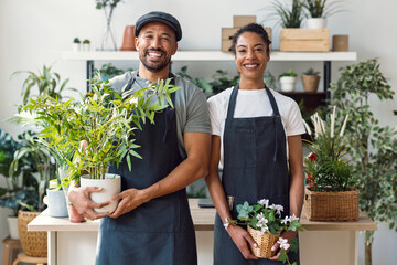 Entrepreneur and seller with apron holding plants in indoor plant store