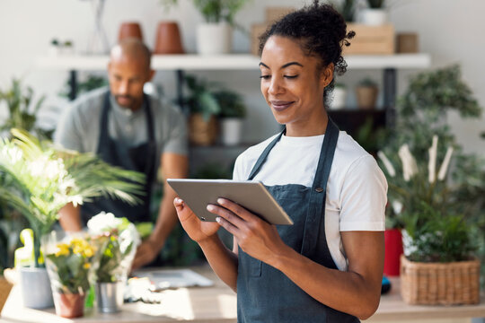 Florist with digital tablet working in plant shop indoors - Powered by Adobe