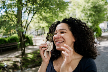 Smiling woman wiping nose with tissue outdoors on sunny summer day