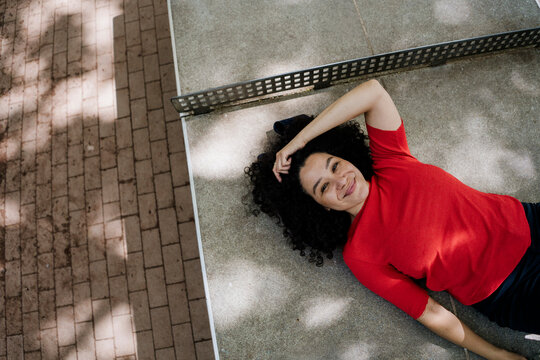 Smiling woman relaxing outdoors on pavement during sunny urban summer break