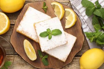 Tasty lemon bars with mint and fresh fruits on wooden table, flat lay