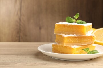 Tasty lemon bars with mint on wooden table, closeup. Space for text