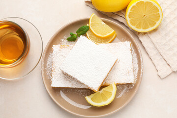Tasty lemon bars with mint, fresh fruits and tea on beige table, flat lay
