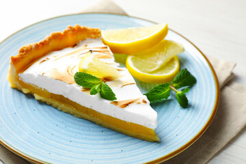 Slice of tasty lemon meringue tart served on white wooden table, closeup