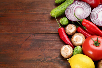 Different fresh raw vegetables and lemon on wooden table, flat lay. Space for text