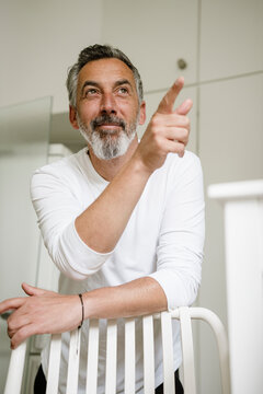 Mature man at home pointing and smiling planning future ideas
