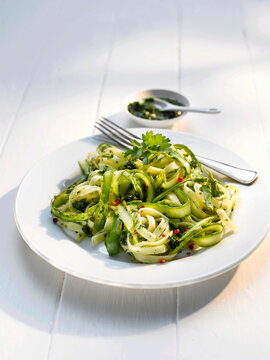 Vegetarian zucchini pasta with wild garlic pesto on white plate