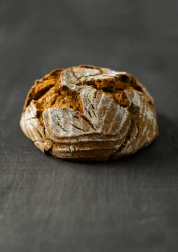 Rustic German Bauernbrot loaf on dark table with flour dusting
