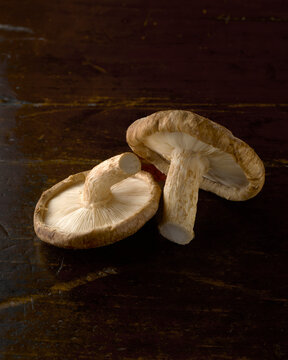 Two shiitake mushrooms on rustic wooden surface
