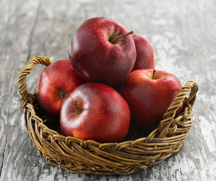 Red Jonagold and Red Delicious apples in basket on rustic wood table