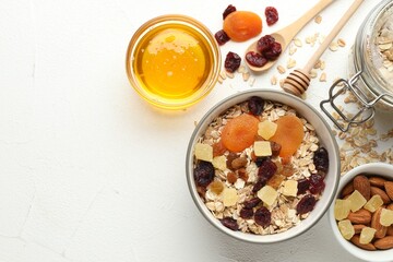 Making granola. Oat flakes, dried fruits and other ingredients on white table, flat lay. Space for text