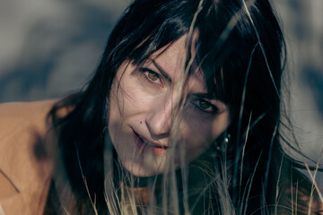 Young caucasian female in nature with long dark hair and thoughtful expression
