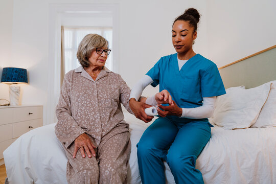 Healthcare professional providing home care assistance wrapping bandage