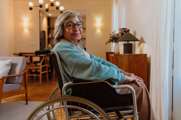 Senior with grey hair and glasses smiling in wheelchair indoors