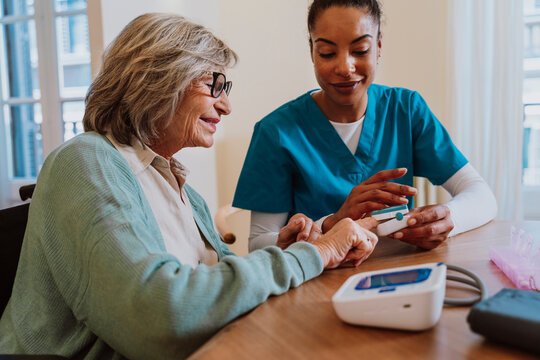 Nurse monitoring oxygen saturation of patient with pulse oximeter