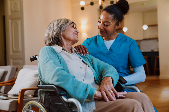 Caregiver assisting elderly woman in wheelchair at home