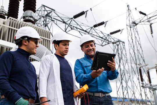 Engineers inspecting electric transformer at wind farm