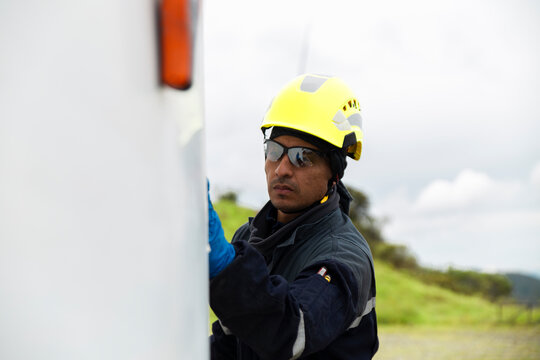 Worker inspecting a wind turbine outdoors wearing safety gear