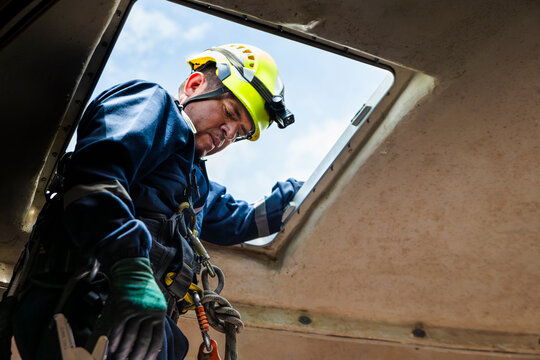 Engineer climbing out of a nacelle on a wind turbine for maintenance and inspection