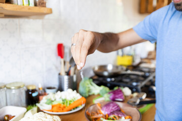 Sprinkling salt on fresh vegetables in a home kitchen