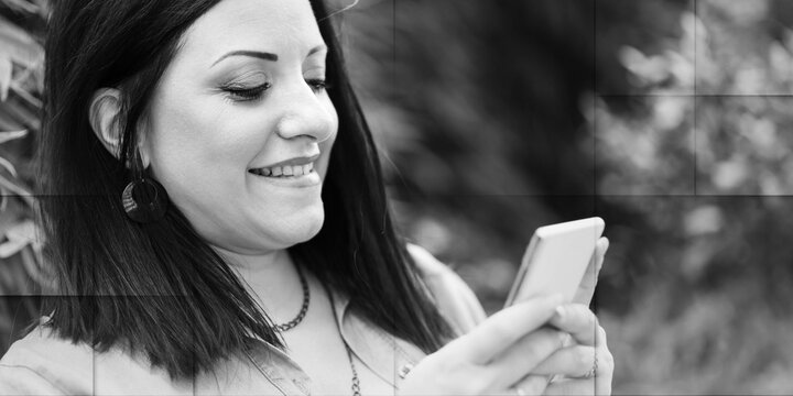 Pretty young woman using her mobile phone, outdoors, geometric pattern - Powered by Adobe