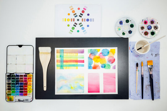 Top view of watercolor painting supplies and colorful art on table