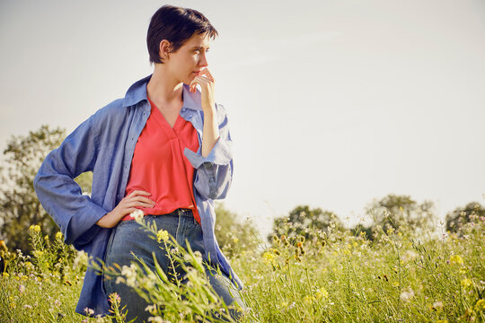Thoughtful young woman standing with on hip in field