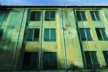 Façade de maison abandonnée derrière une bâche transparente.