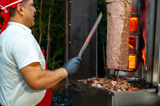 Meat rotisserie at the luxury hotel's buffet. A rotisserie chef is carving traditional Turkish rotisserie meat.Hatay usulu et tavuk doner durum. Lavash doner kebab ( zurna  durum )  or shawarma sliced