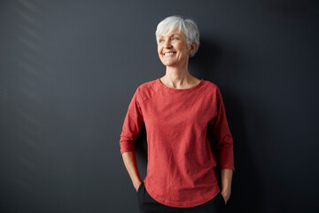 Smiling woman in red shirt enjoying a break indoors with sunlight