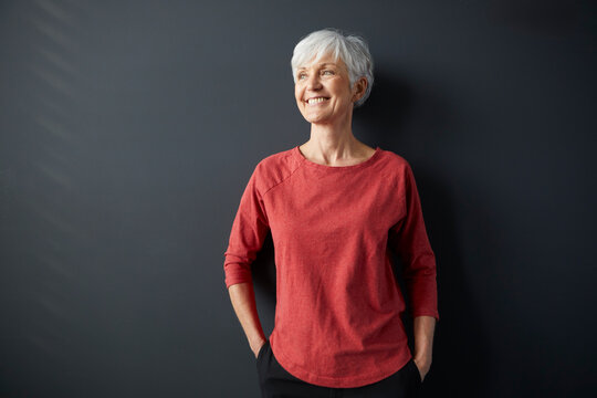 Smiling woman in red shirt enjoying a break indoors with sunlight