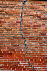 Mur de brique  avec grande fissure verticale.